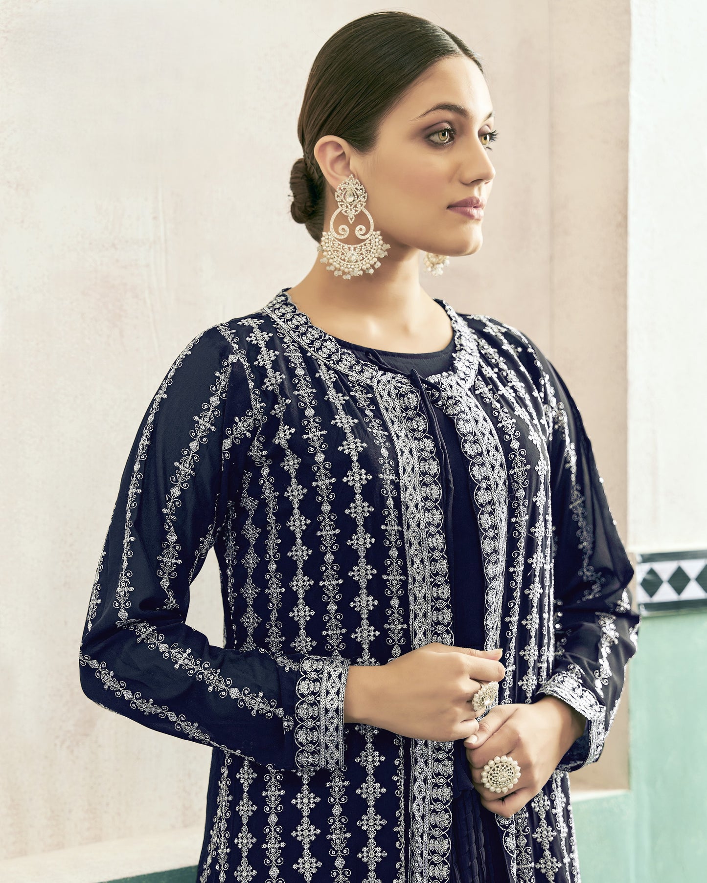 Woman wearing a navy blue embroidered outfit with silver details against a light background