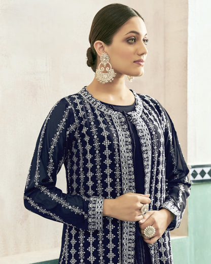Woman wearing a navy blue embroidered outfit with silver details against a light background