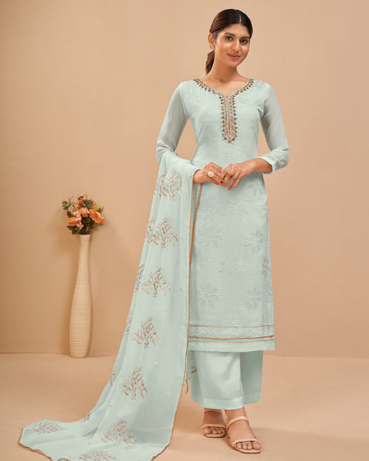 Woman wearing a light blue embroidered traditional outfit on a beige background