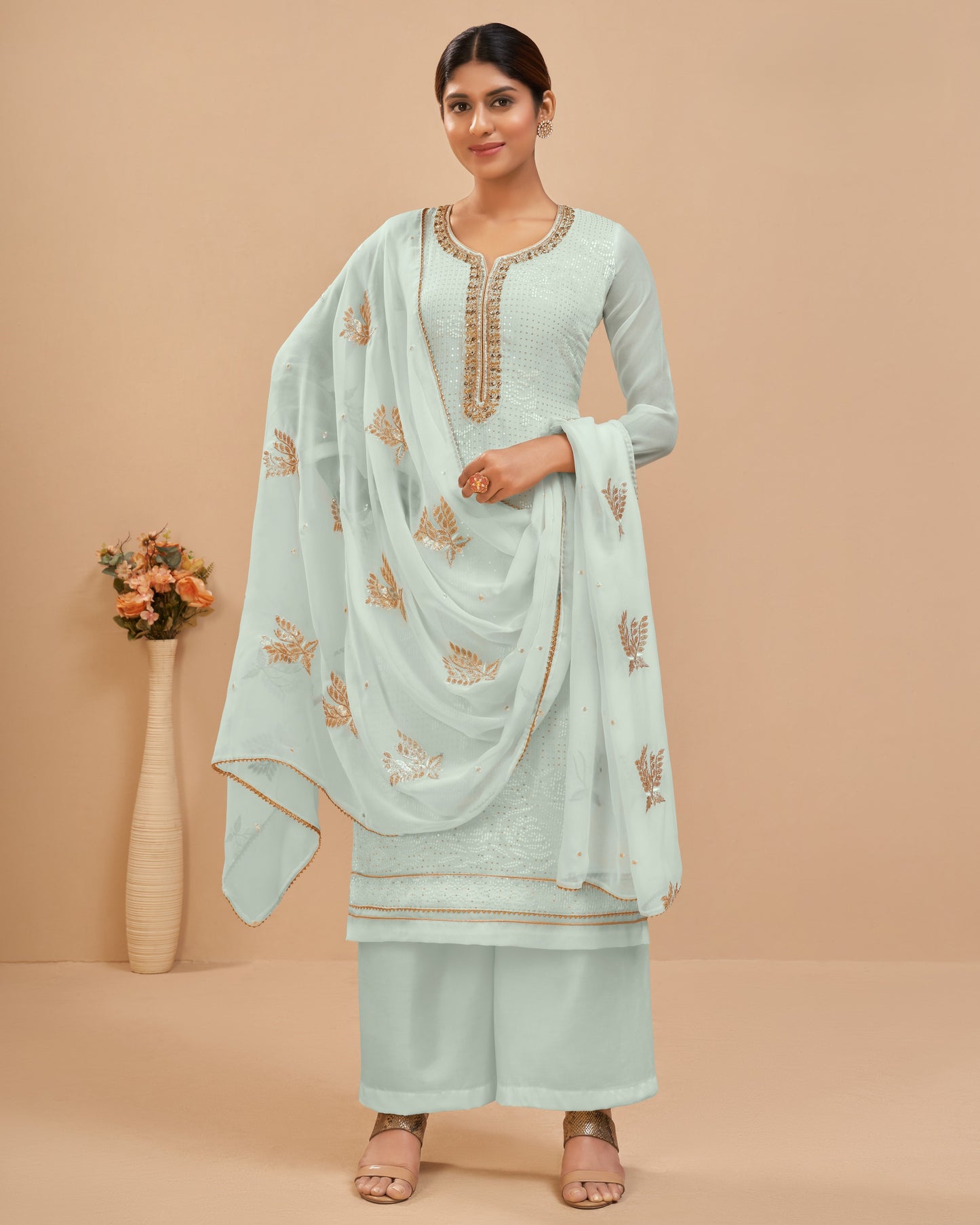 Woman wearing a light blue traditional outfit with embroidery on a beige background