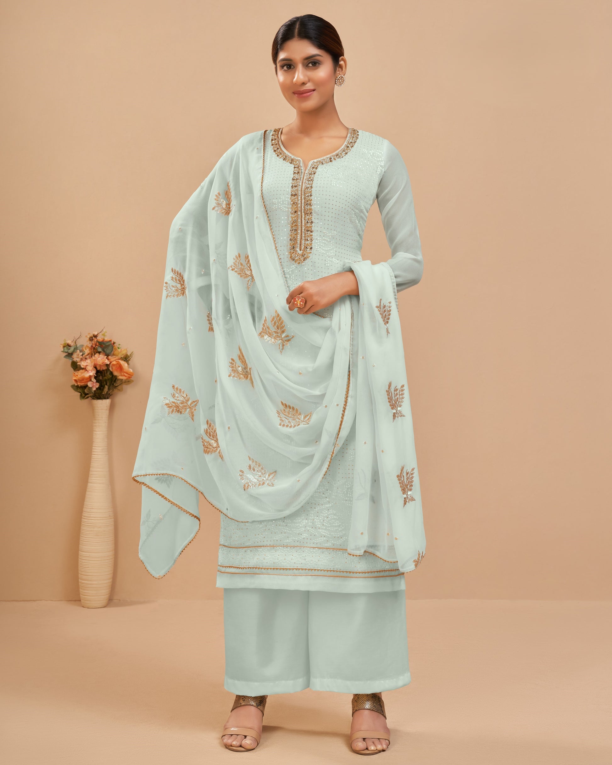 Woman wearing a light blue traditional outfit with embroidery on a beige background