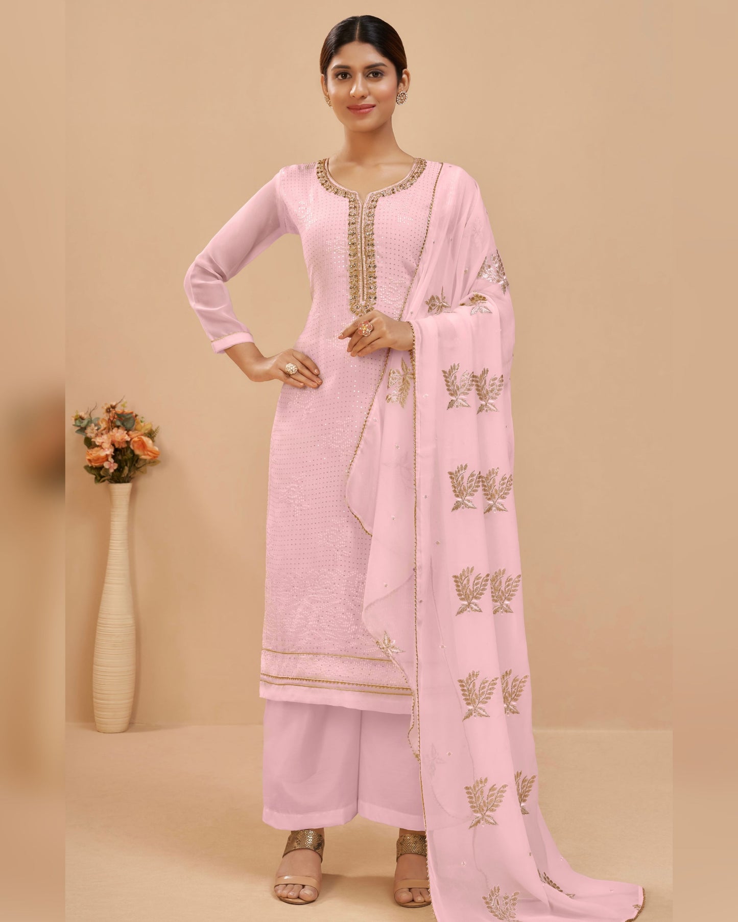 Woman wearing a pink traditional outfit with a matching dupatta on a beige background