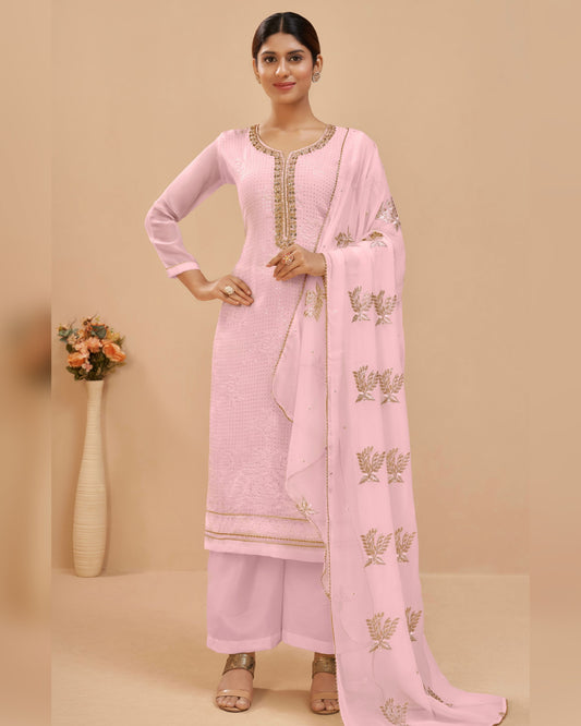 Woman wearing a pink traditional outfit with a matching dupatta on a beige background