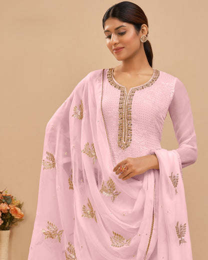 Woman wearing a pink embroidered traditional outfit with a beige background