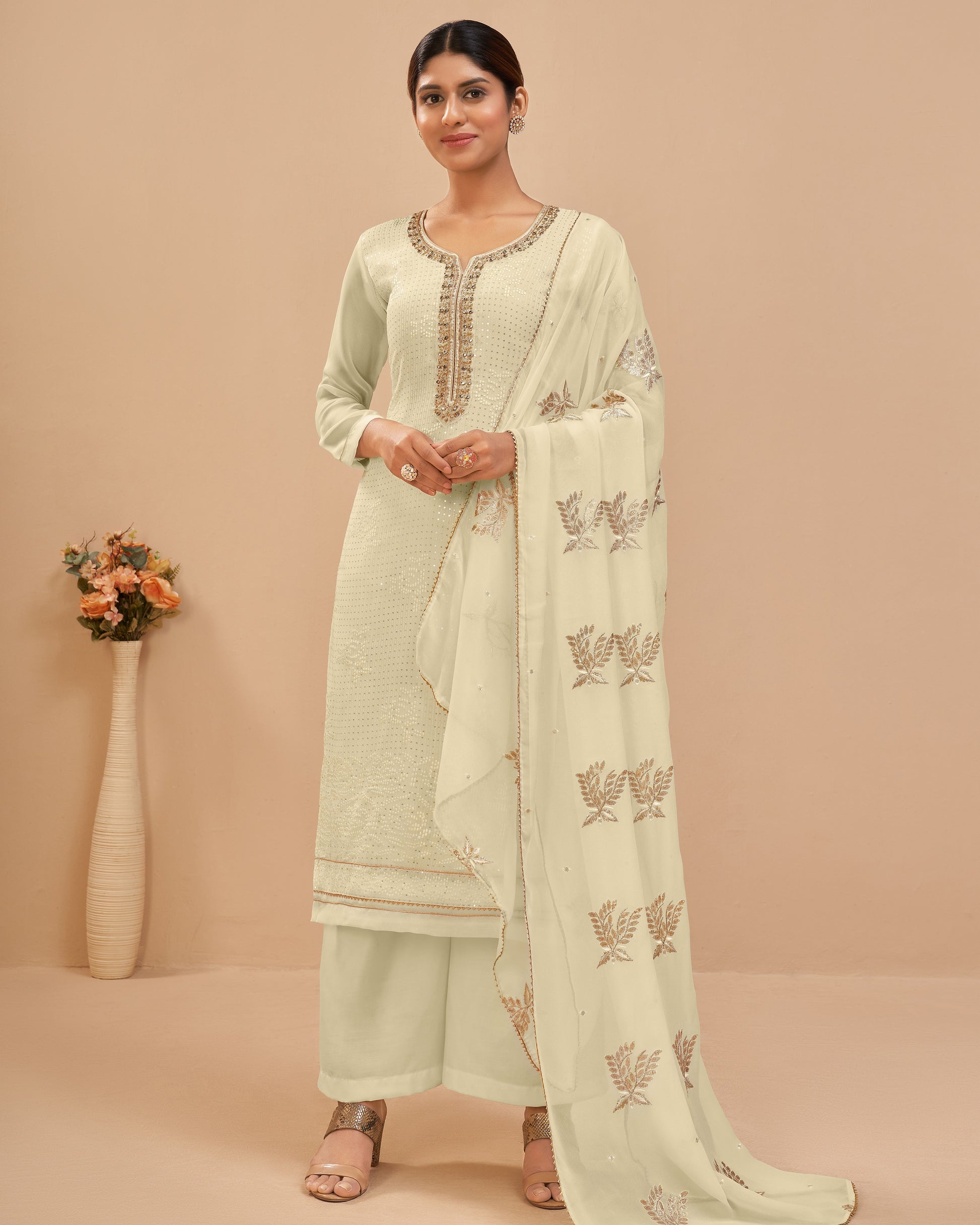 Woman wearing a light green traditional outfit with a matching dupatta on a beige background