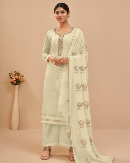 Woman wearing a light green traditional outfit with a matching dupatta on a beige background