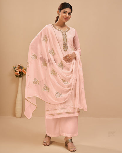 Woman wearing a light pink traditional outfit with a matching dupatta on a beige background