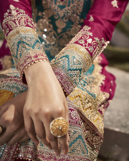 Close-up of a hand wearing a gold ring with intricate jewelry and clothing.