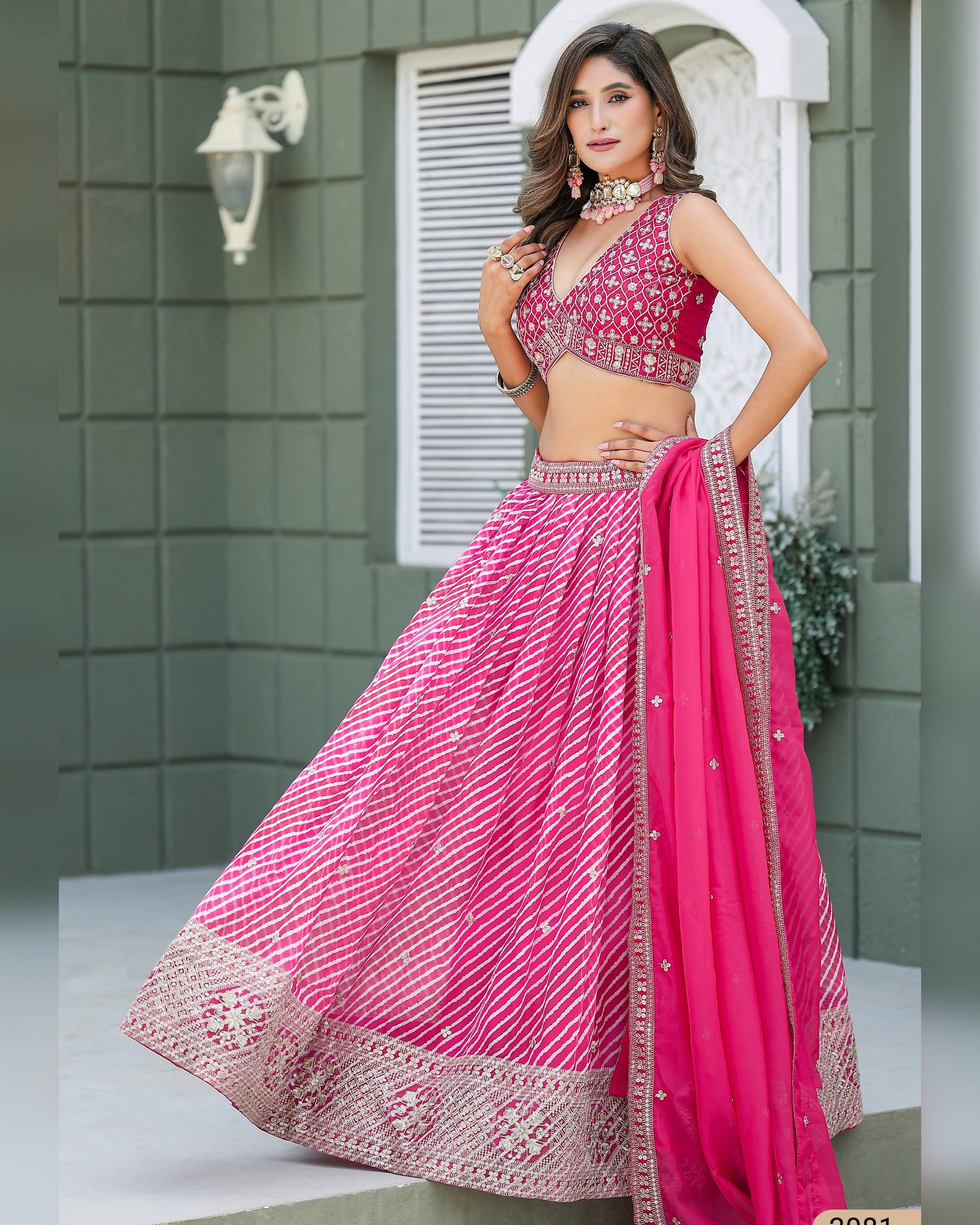 Woman wearing a pink traditional outfit with intricate designs in an outdoor setting.