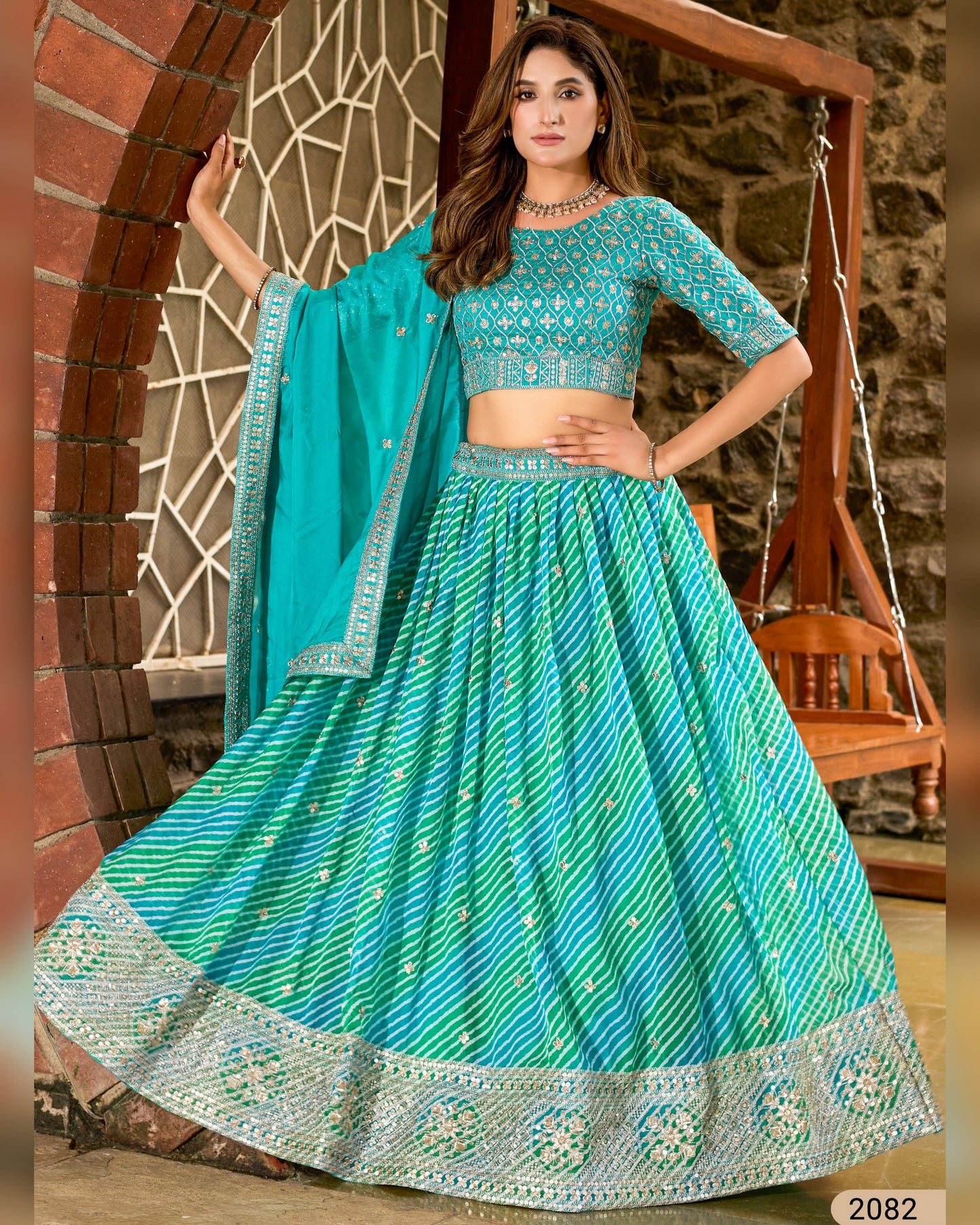 Woman wearing a traditional turquoise and green embroidered outfit with a matching dupatta.