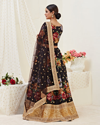 Woman wearing a black floral lehenga with gold border in a decorated room.