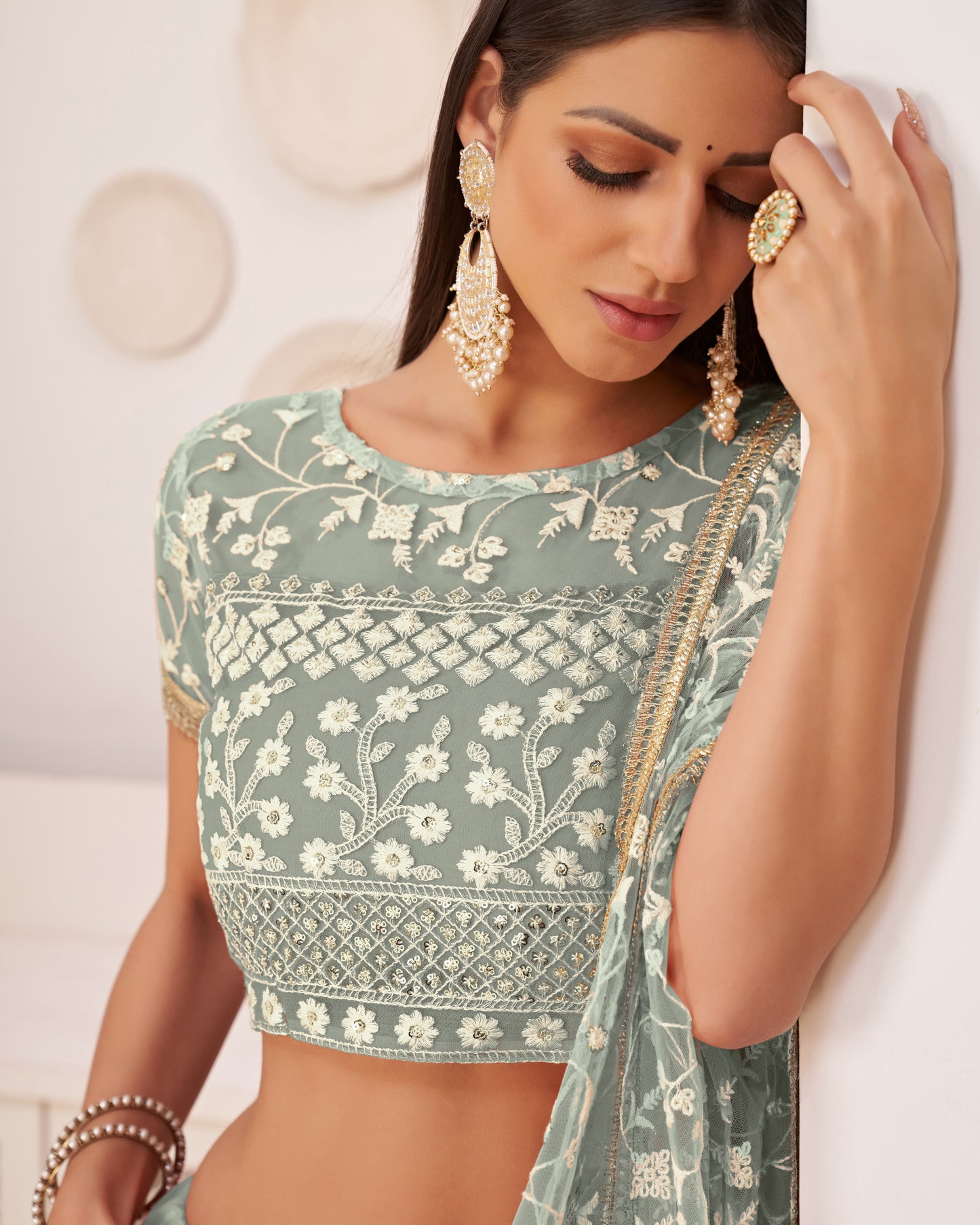 Woman wearing a green embroidered blouse with a plain background