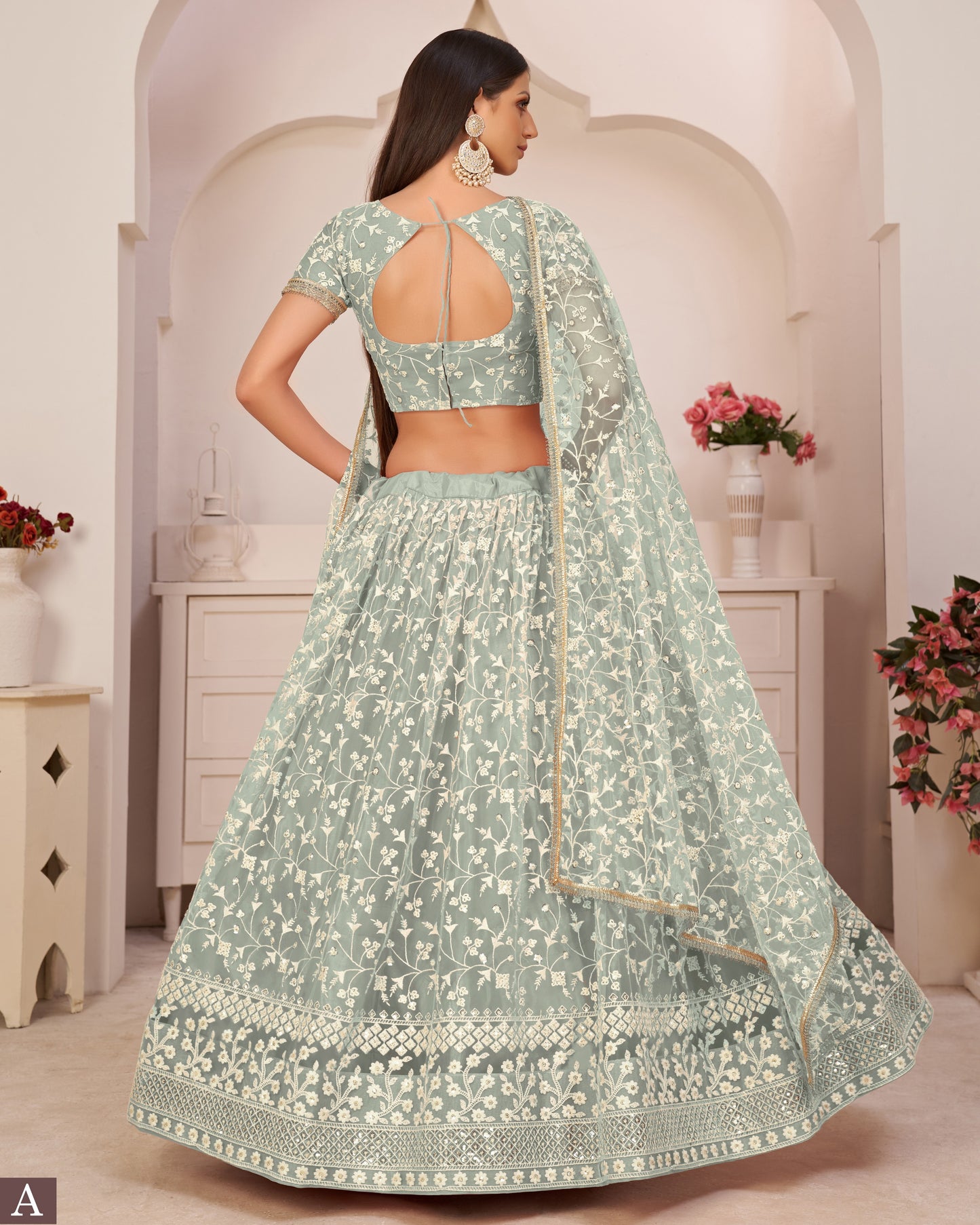 Woman wearing a light green floral lehenga in an elegant indoor setting.
