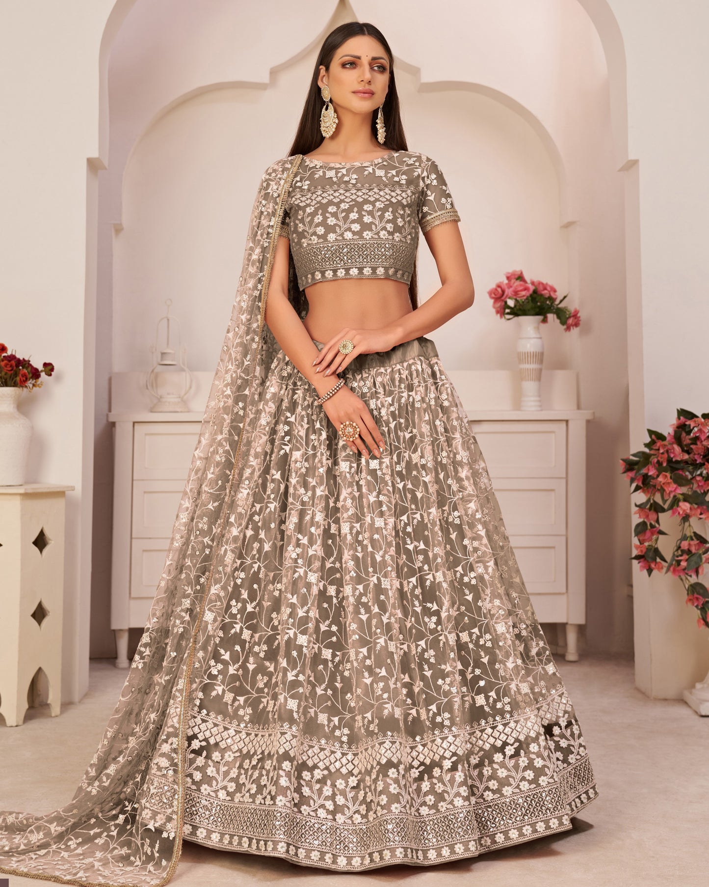 Woman in traditional embroidered outfit with floral decorations in a decorated room.