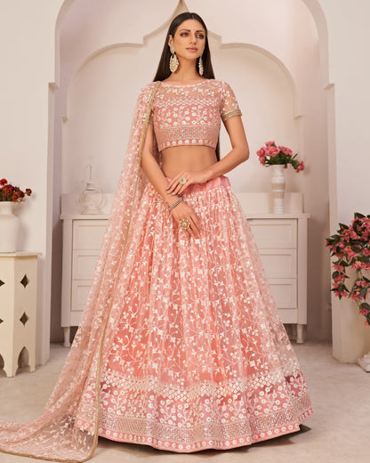 Woman wearing a pink embroidered traditional outfit in a decorated room.