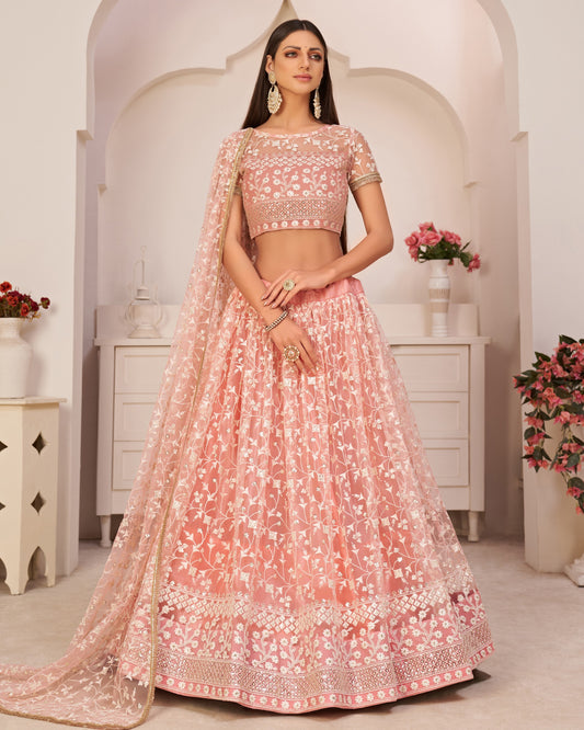 Woman wearing a pink embroidered traditional outfit in a decorated room.