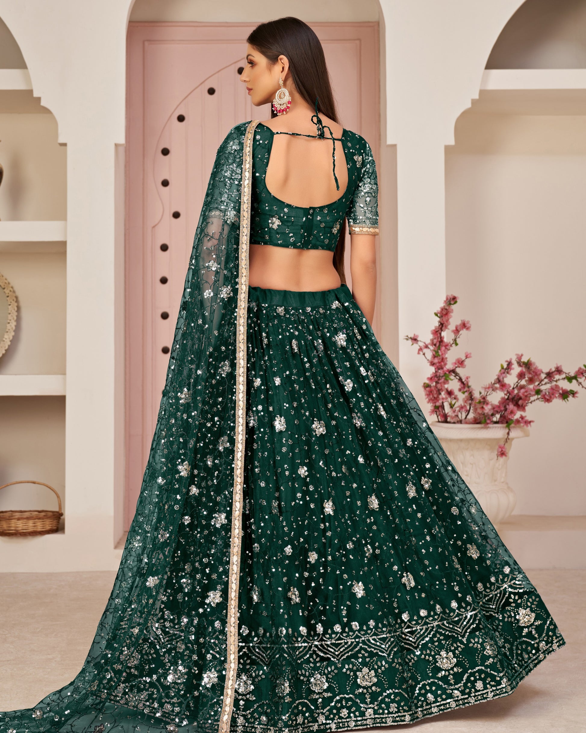 Woman wearing a green embroidered traditional outfit in an elegant indoor setting.