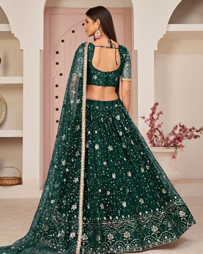 Woman wearing a green embroidered traditional outfit in an elegant indoor setting.