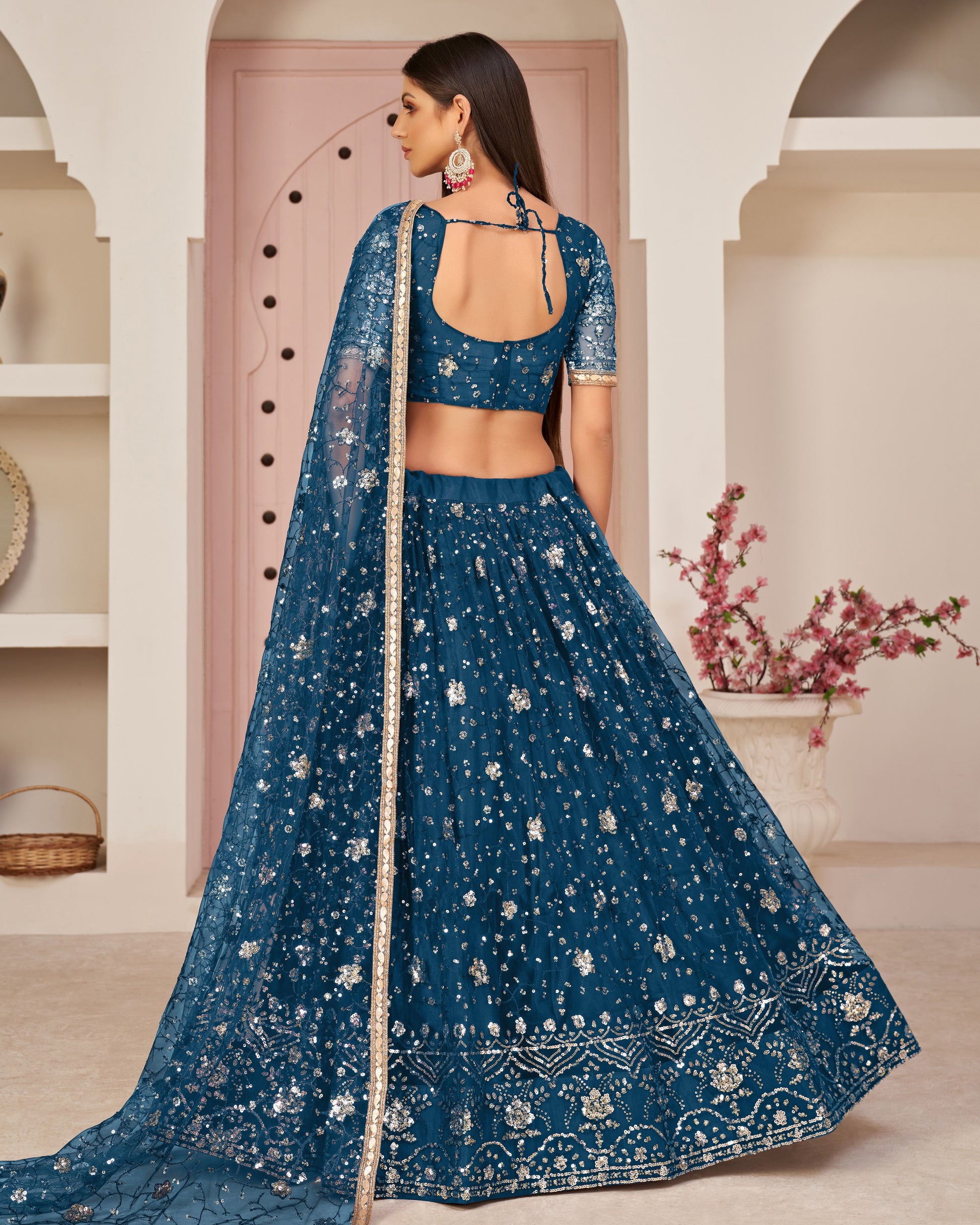 Woman wearing a blue embroidered traditional outfit in an elegant indoor setting.