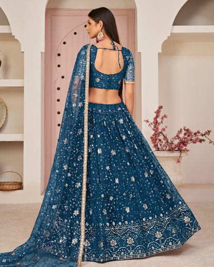 Woman wearing a blue embroidered traditional outfit in an elegant indoor setting.