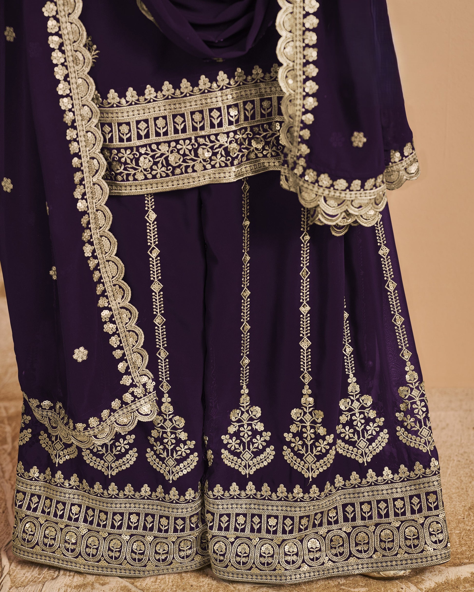 Purple traditional outfit with intricate white embroidery on a beige background