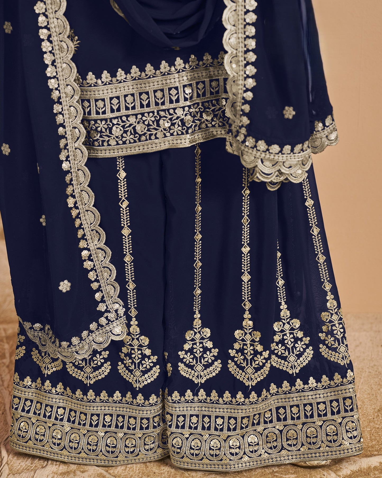 Navy blue traditional outfit with intricate white embroidery on a beige background