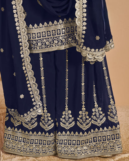 Navy blue traditional outfit with intricate white embroidery on a beige background