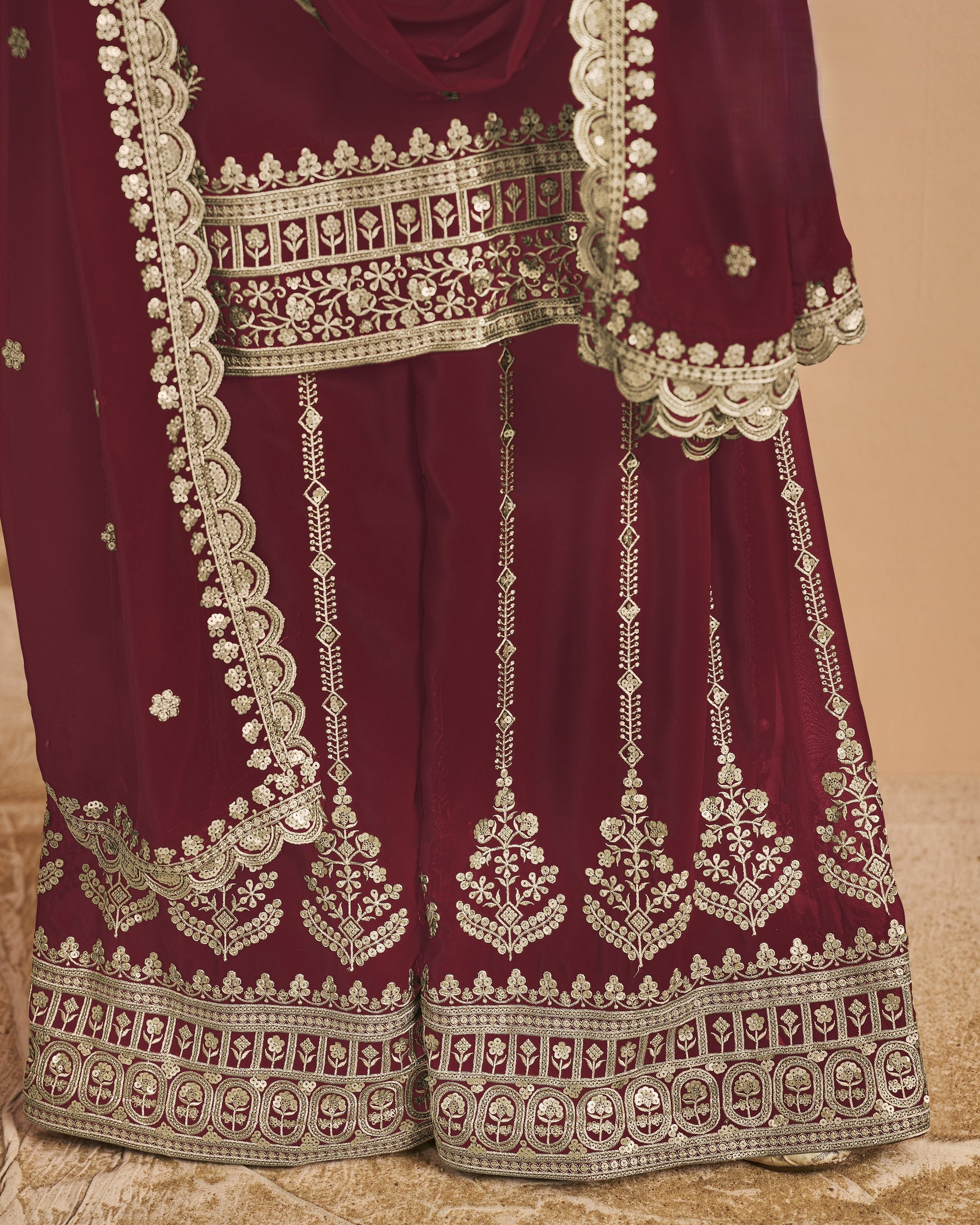 Maroon traditional outfit with intricate white embroidery on a beige background