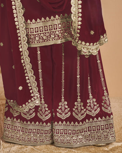 Maroon traditional outfit with intricate white embroidery on a beige background
