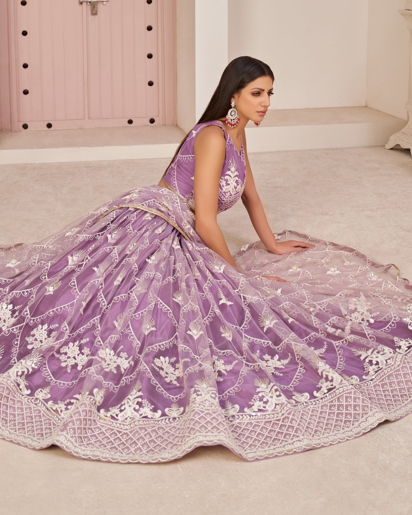Woman in a purple embroidered traditional outfit sitting on the floor.