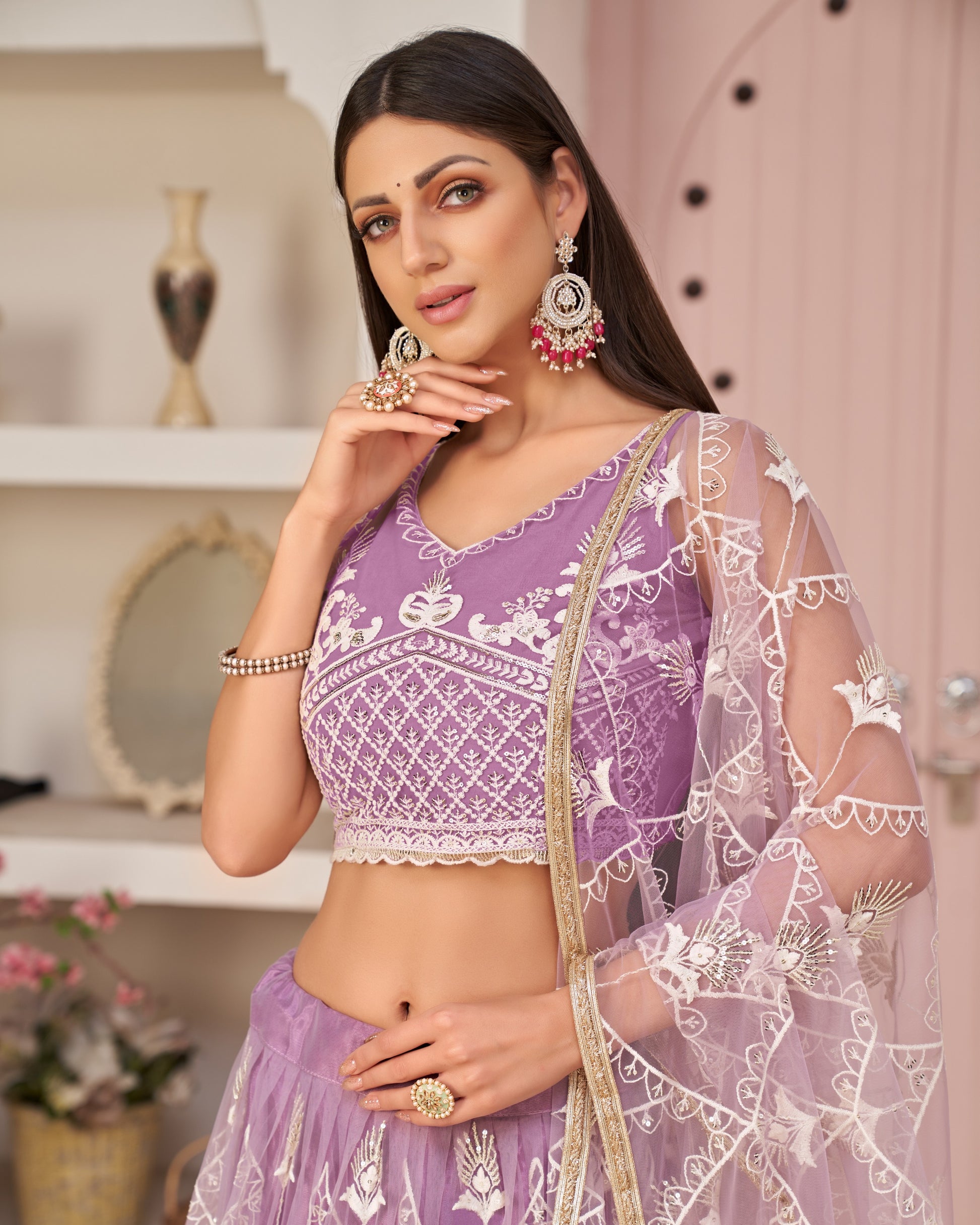Woman wearing a purple traditional outfit with white embroidery in an indoor setting.