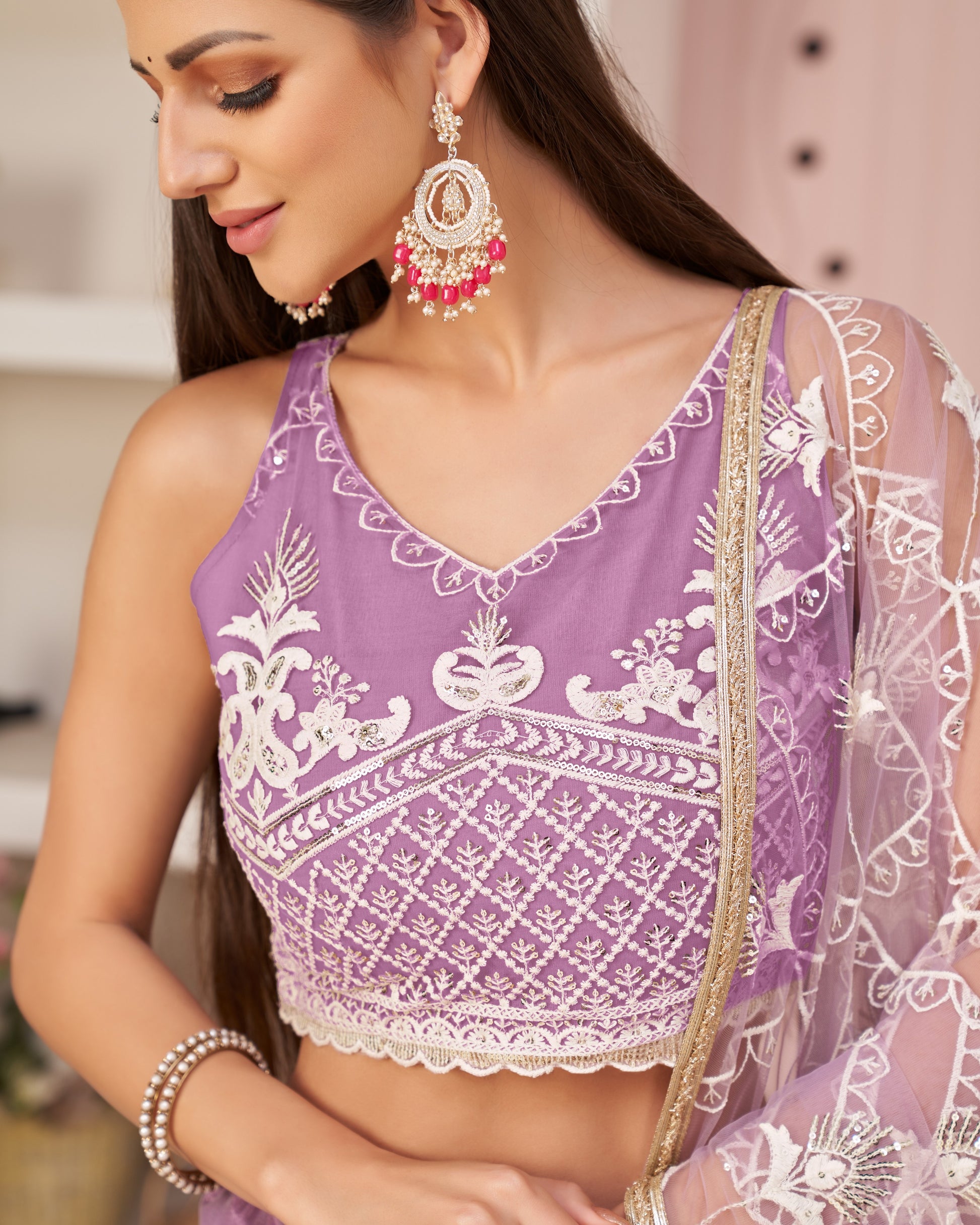 Woman wearing a purple blouse with white embroidery and a sheer dupatta.