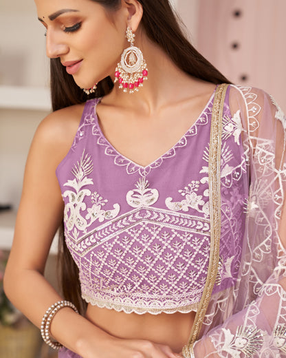 Woman wearing a purple blouse with white embroidery and a sheer dupatta.