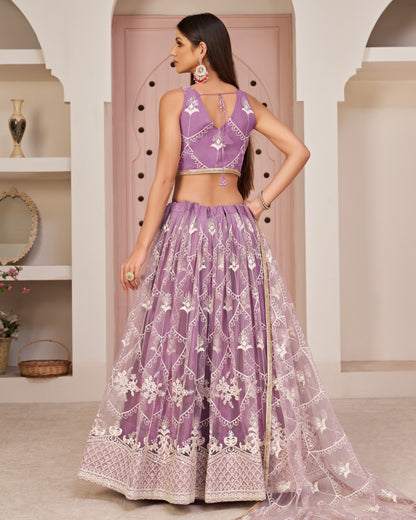 Woman wearing a purple embroidered traditional outfit in an indoor setting.