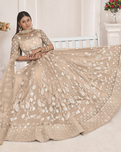 Woman wearing a beige embroidered saree in a well-lit room.