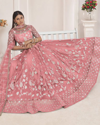 Woman wearing a pink embroidered saree with a white background