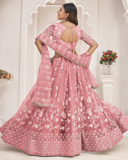 Woman wearing a pink traditional outfit with white patterns in a decorative setting.