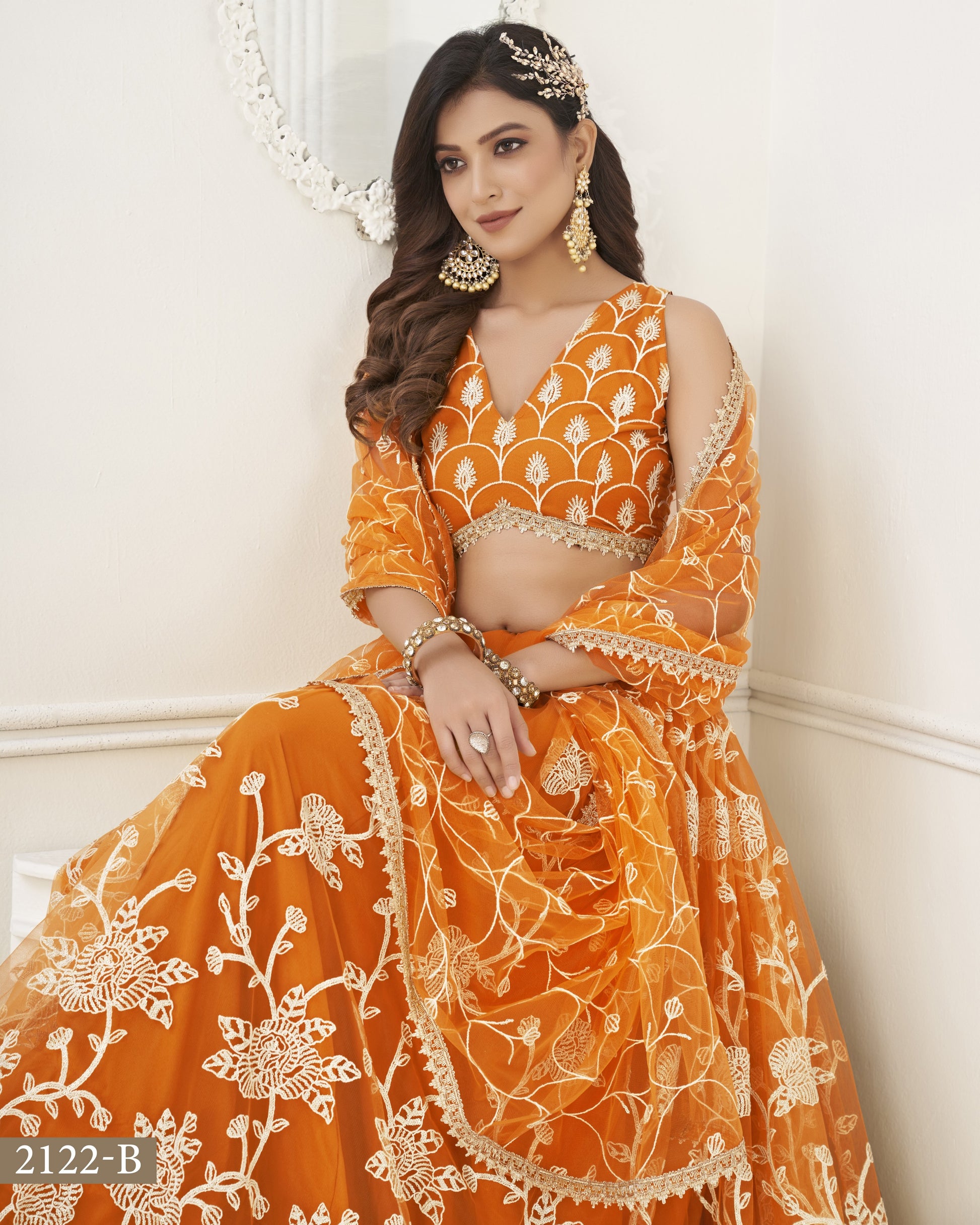 Woman wearing an orange embroidered traditional outfit with white patterns on a white background