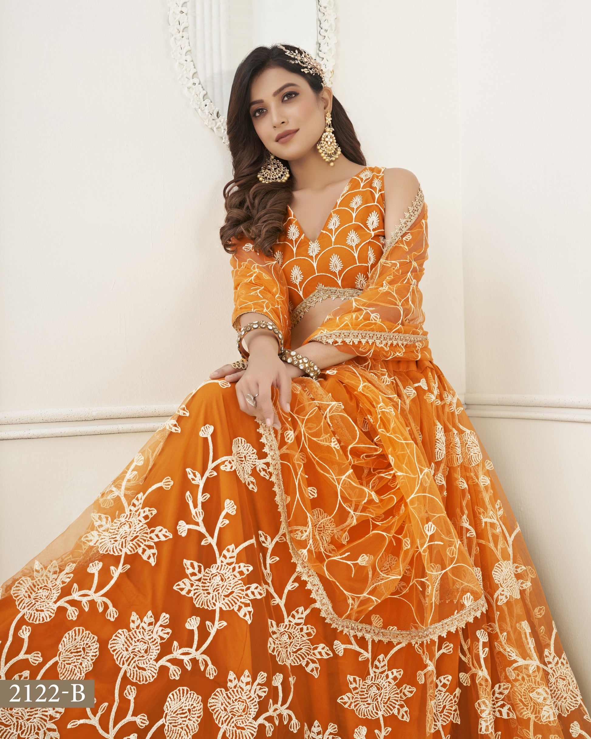 Woman wearing an orange and white embroidered traditional outfit against a white background