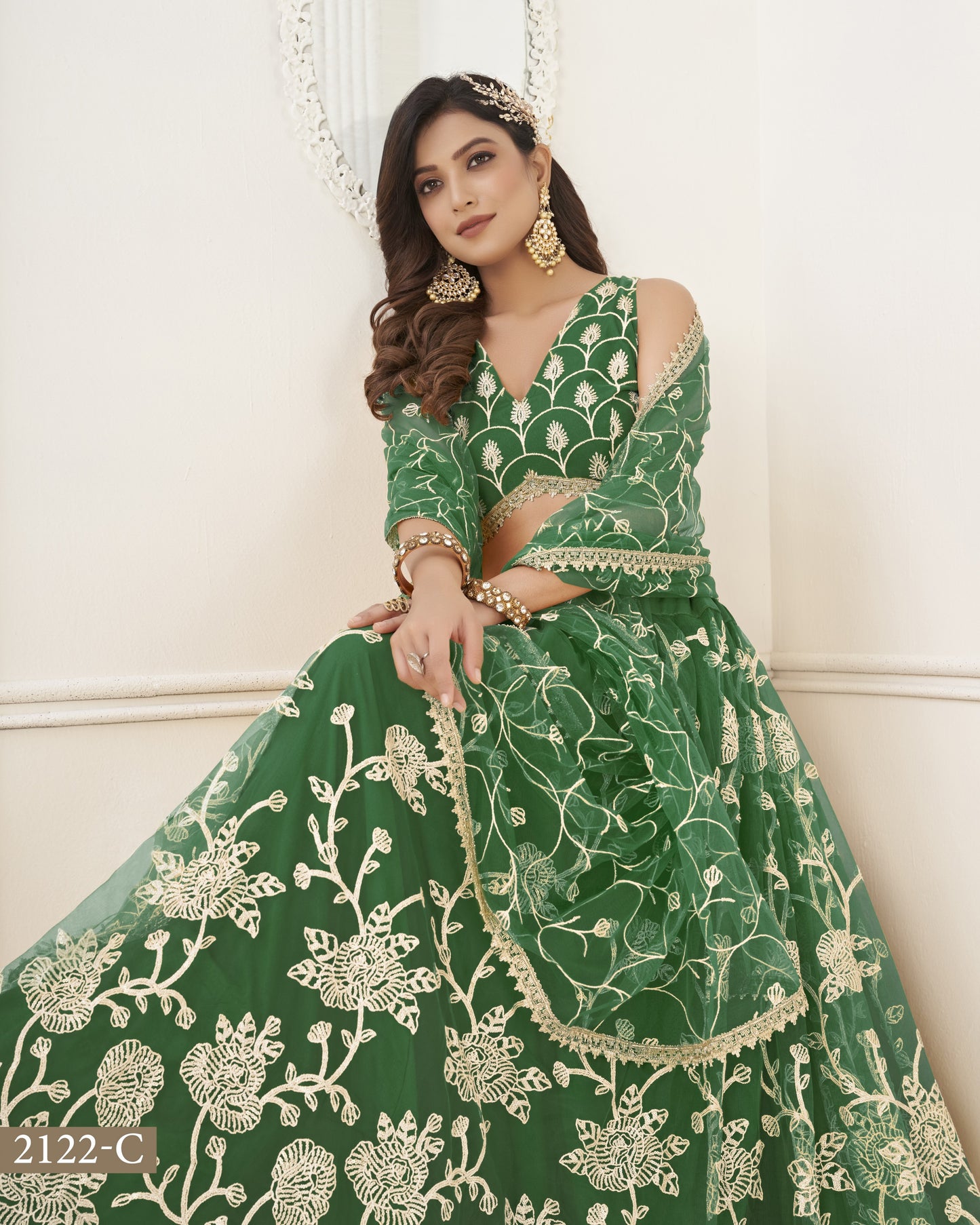 Woman wearing a green embroidered traditional outfit with a white background
