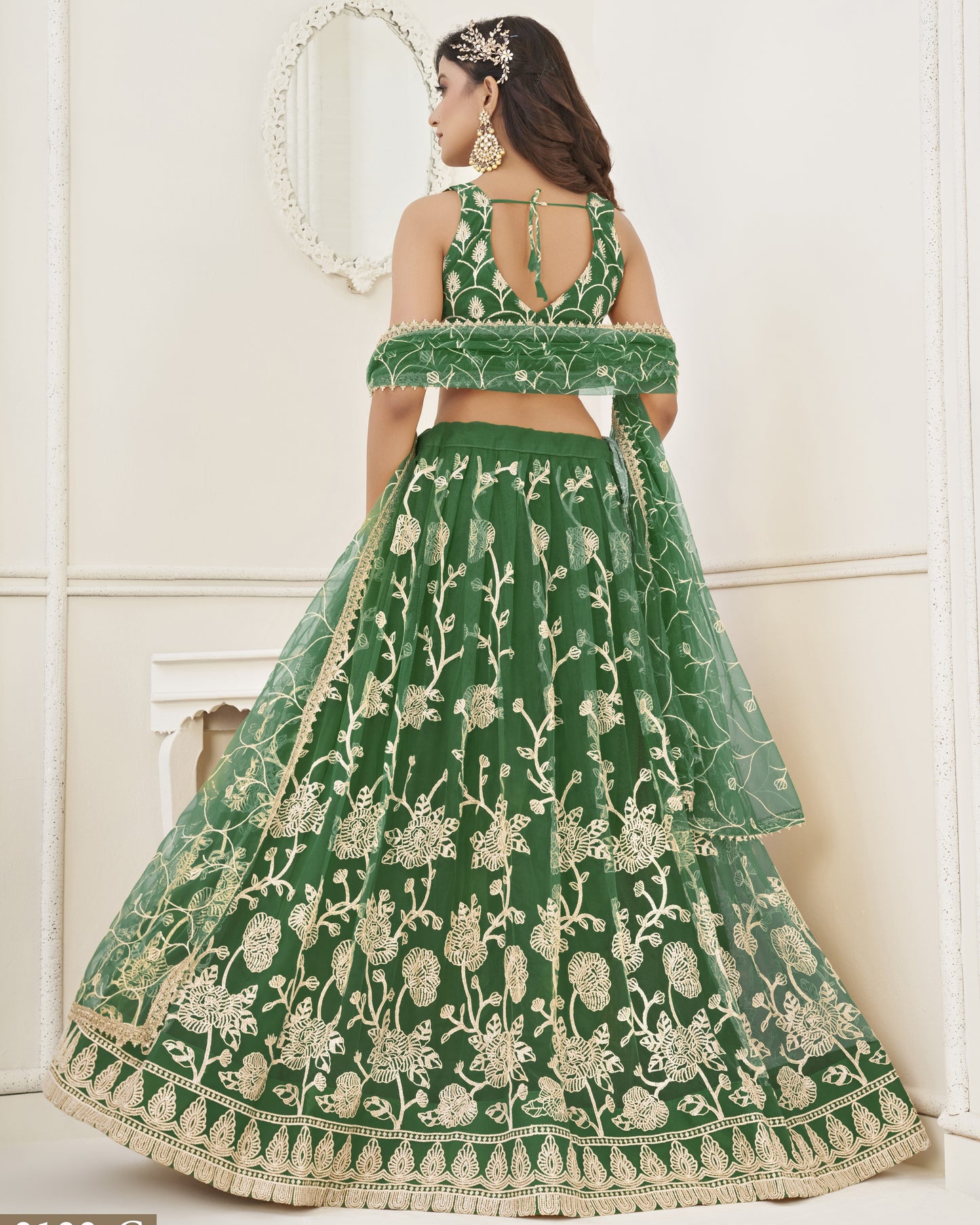 Green embroidered lehenga with gold detailing on a white background