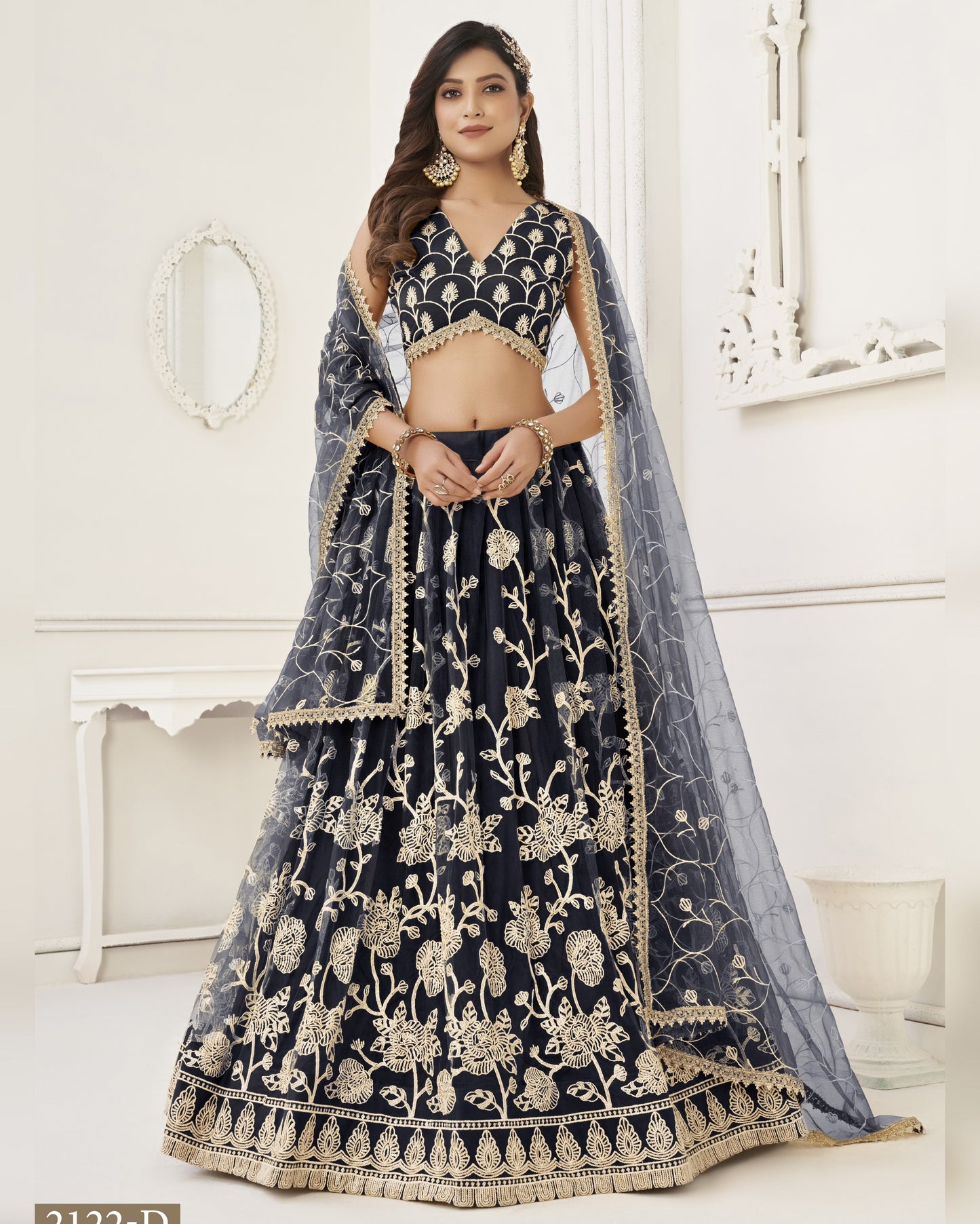 Woman wearing a black and gold embroidered lehenga with a white background
