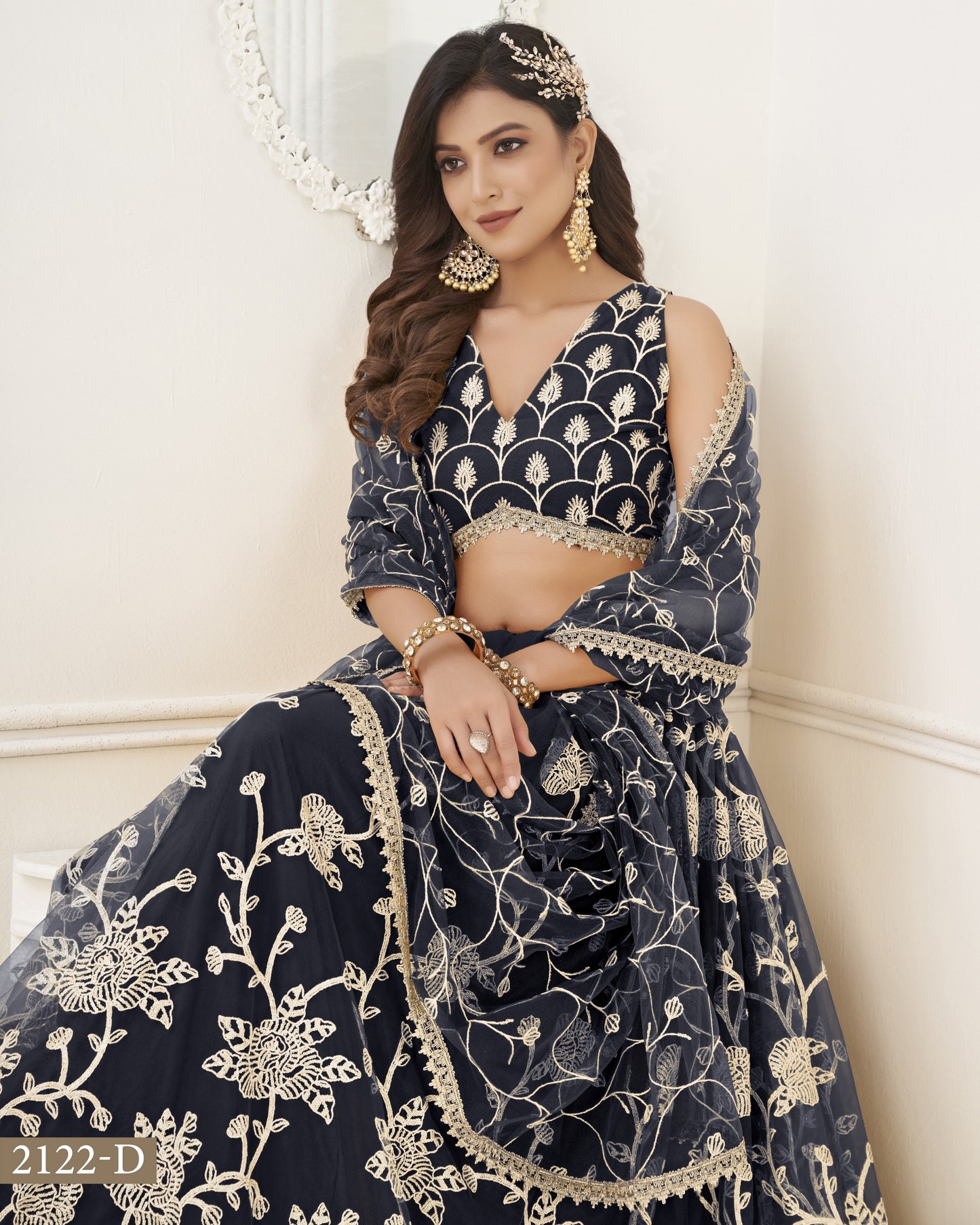 Woman wearing a navy blue embroidered traditional outfit with gold details against a white background