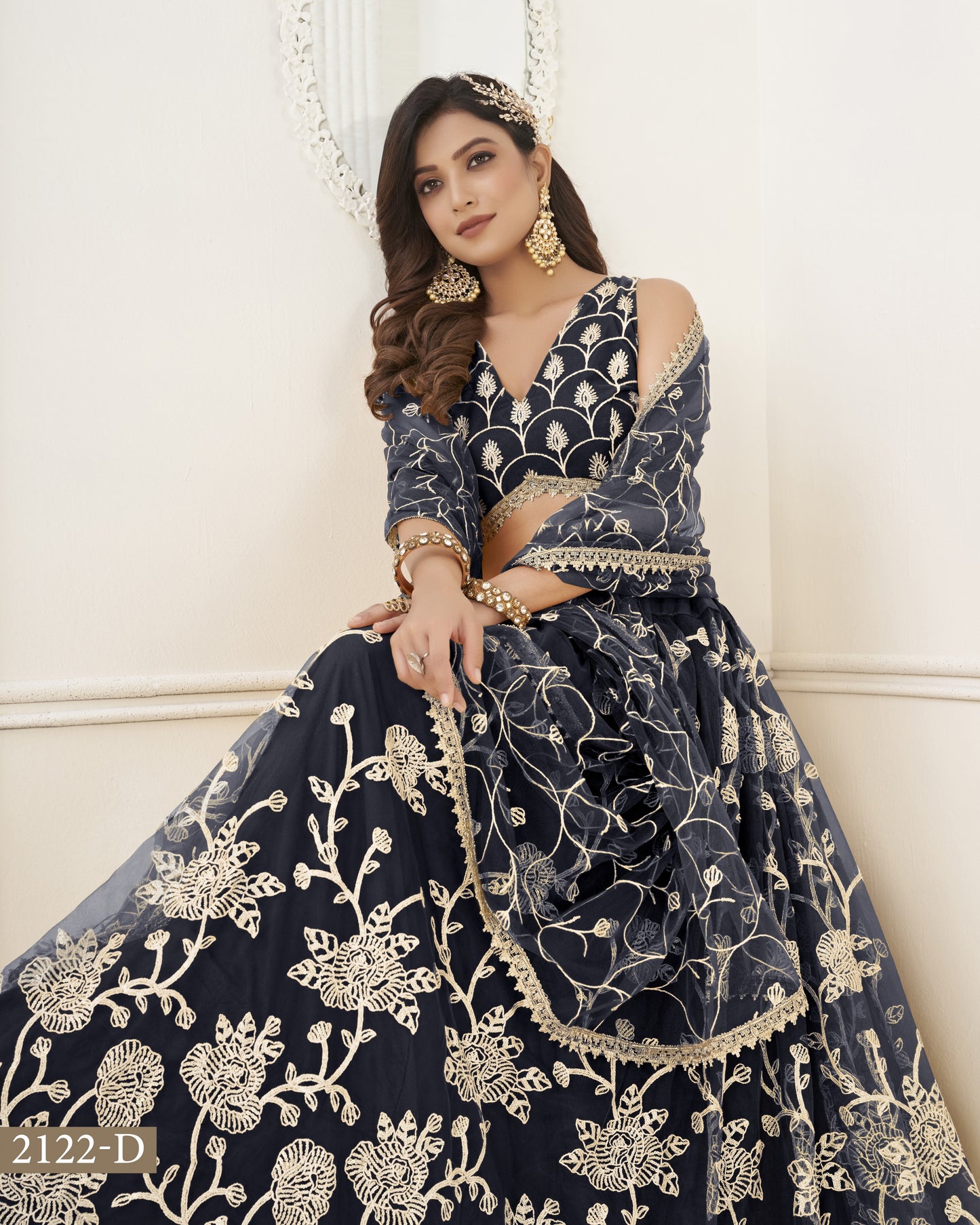 Woman wearing a navy blue embroidered traditional outfit with gold details against a white background