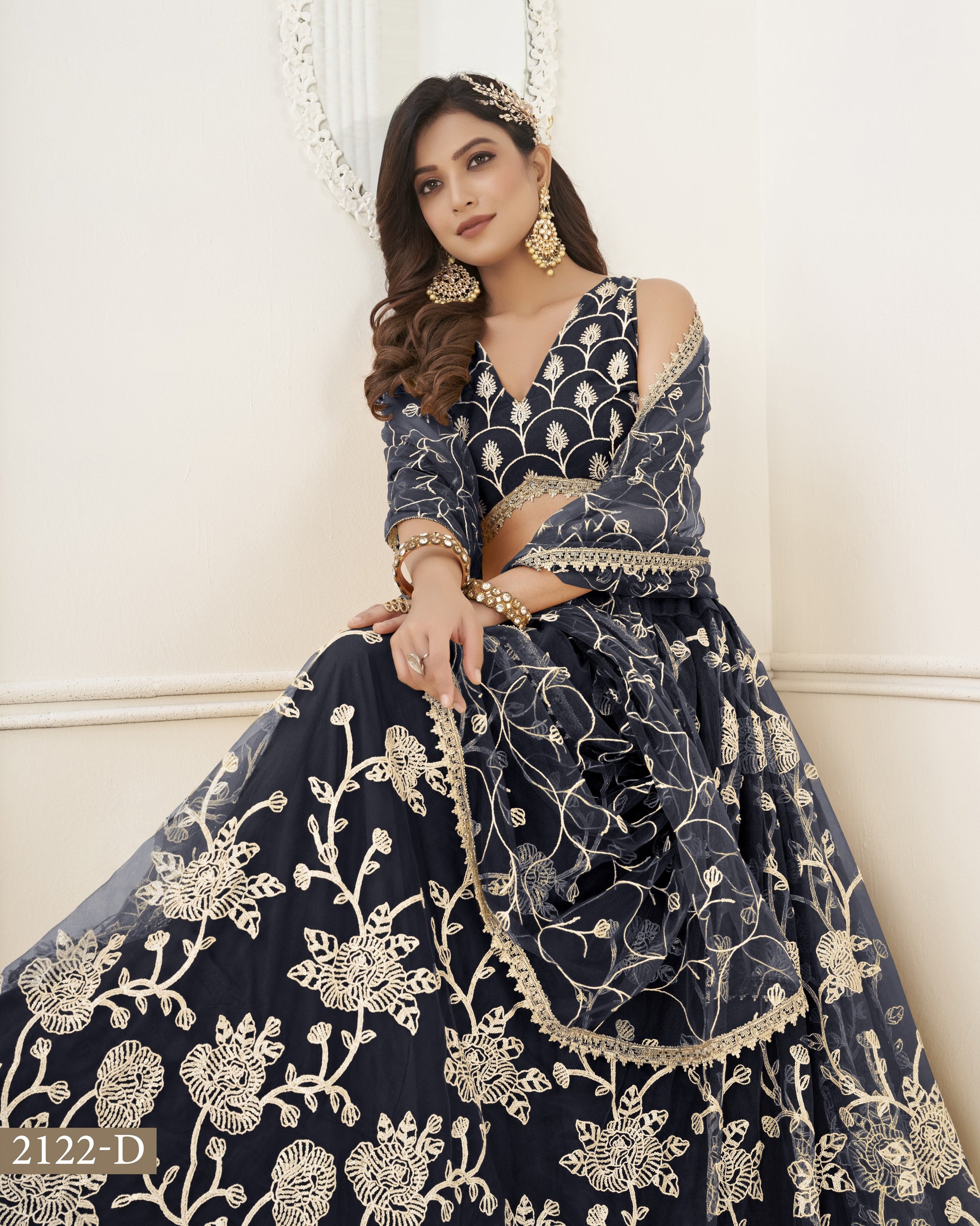Woman wearing a navy blue embroidered traditional outfit with gold details against a white background