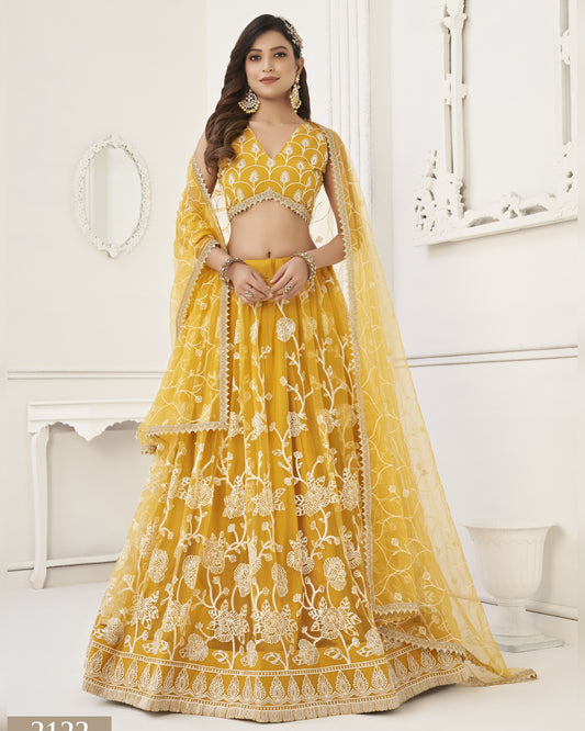Woman wearing a yellow embroidered lehenga in a white room
