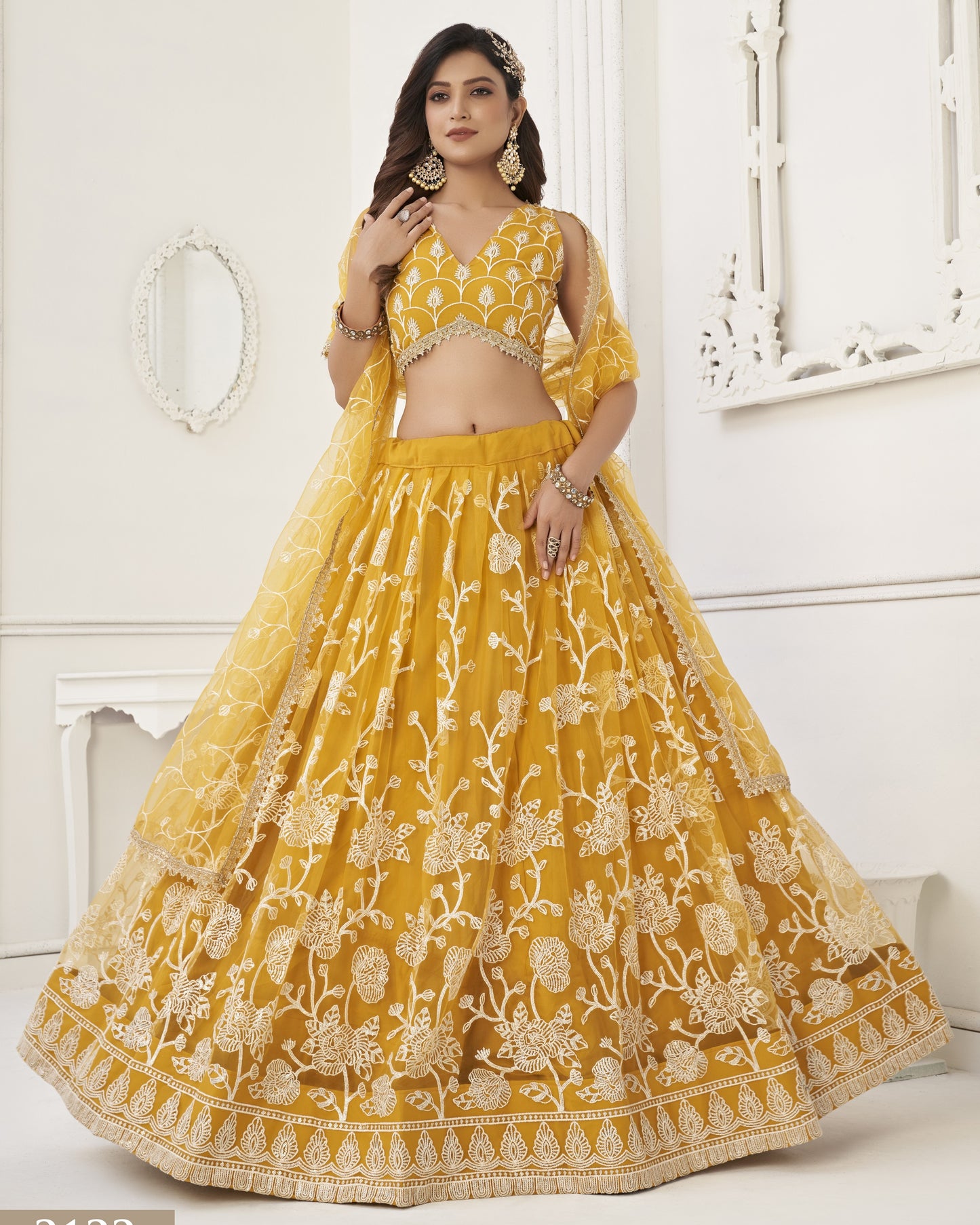 Woman wearing a yellow embroidered traditional outfit in a white room.