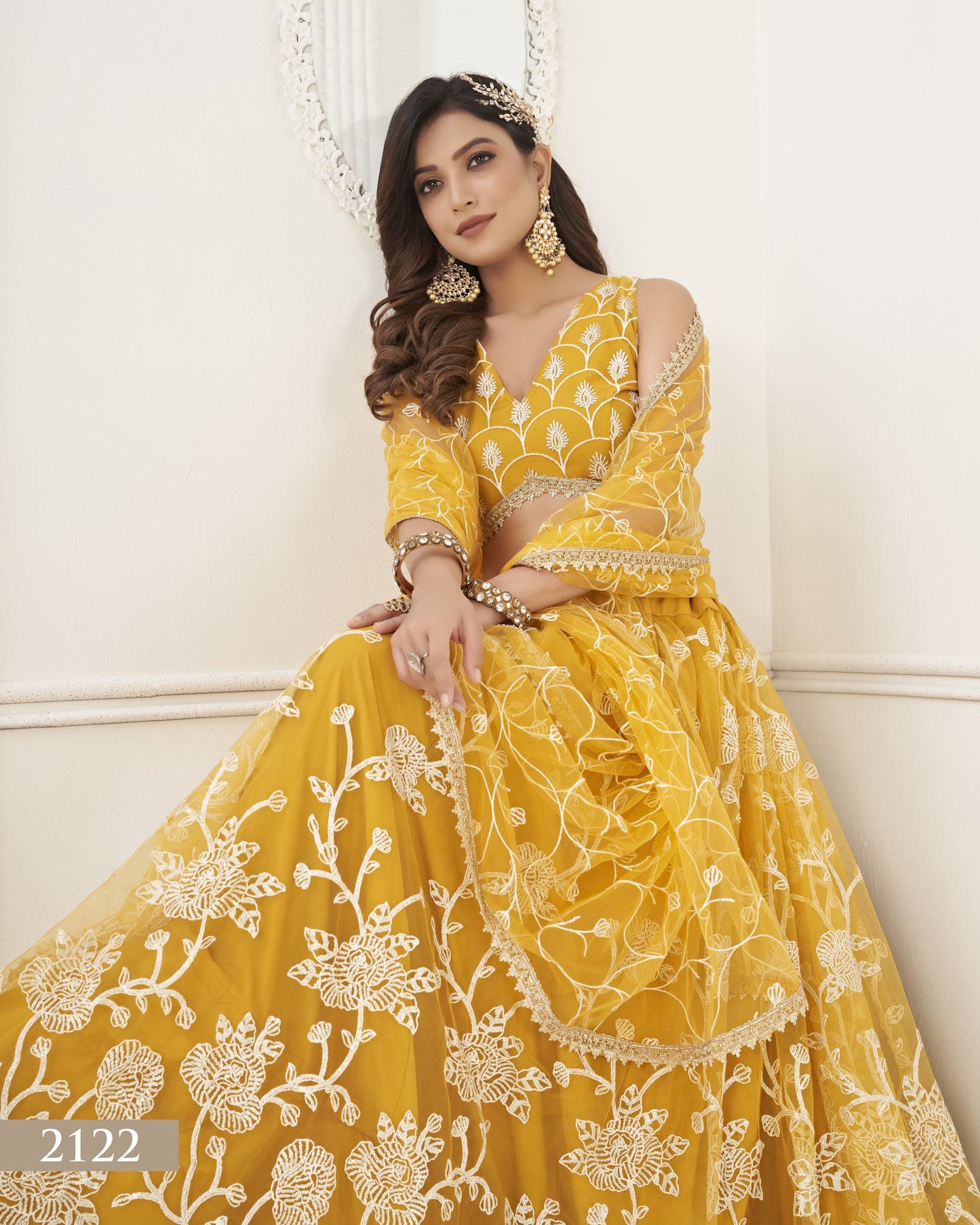 Woman wearing a yellow embroidered dress with floral patterns on a white background