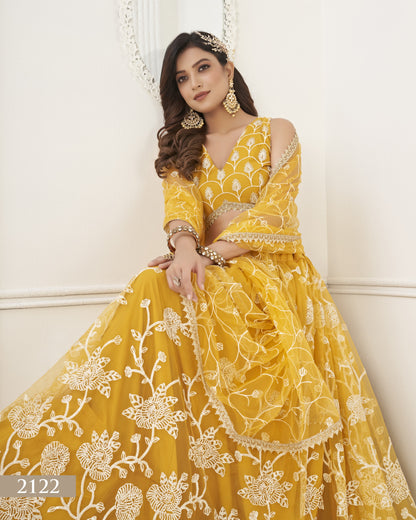 Woman wearing a yellow embroidered dress with floral patterns on a white background