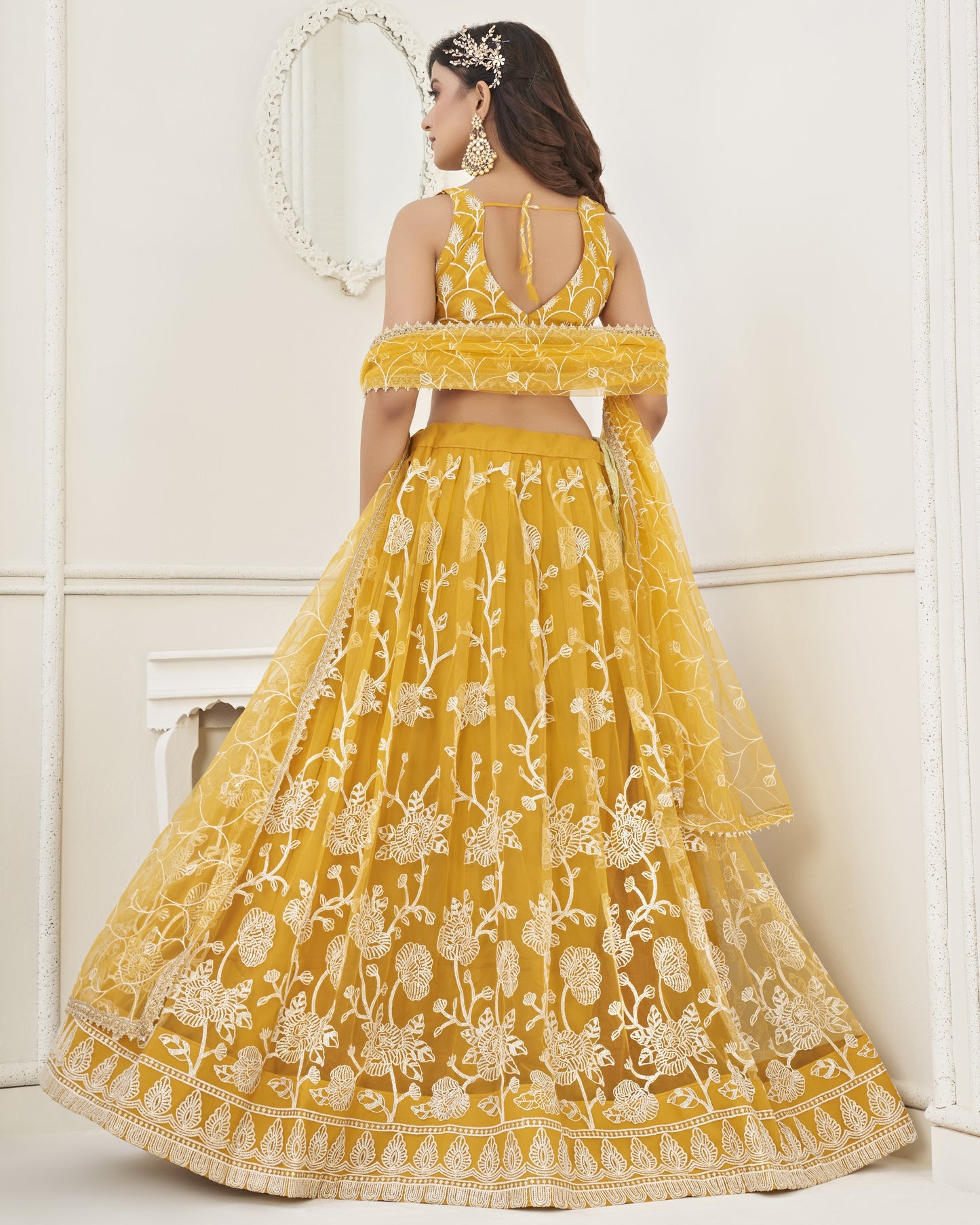 Woman wearing a yellow embroidered lehenga with a white background